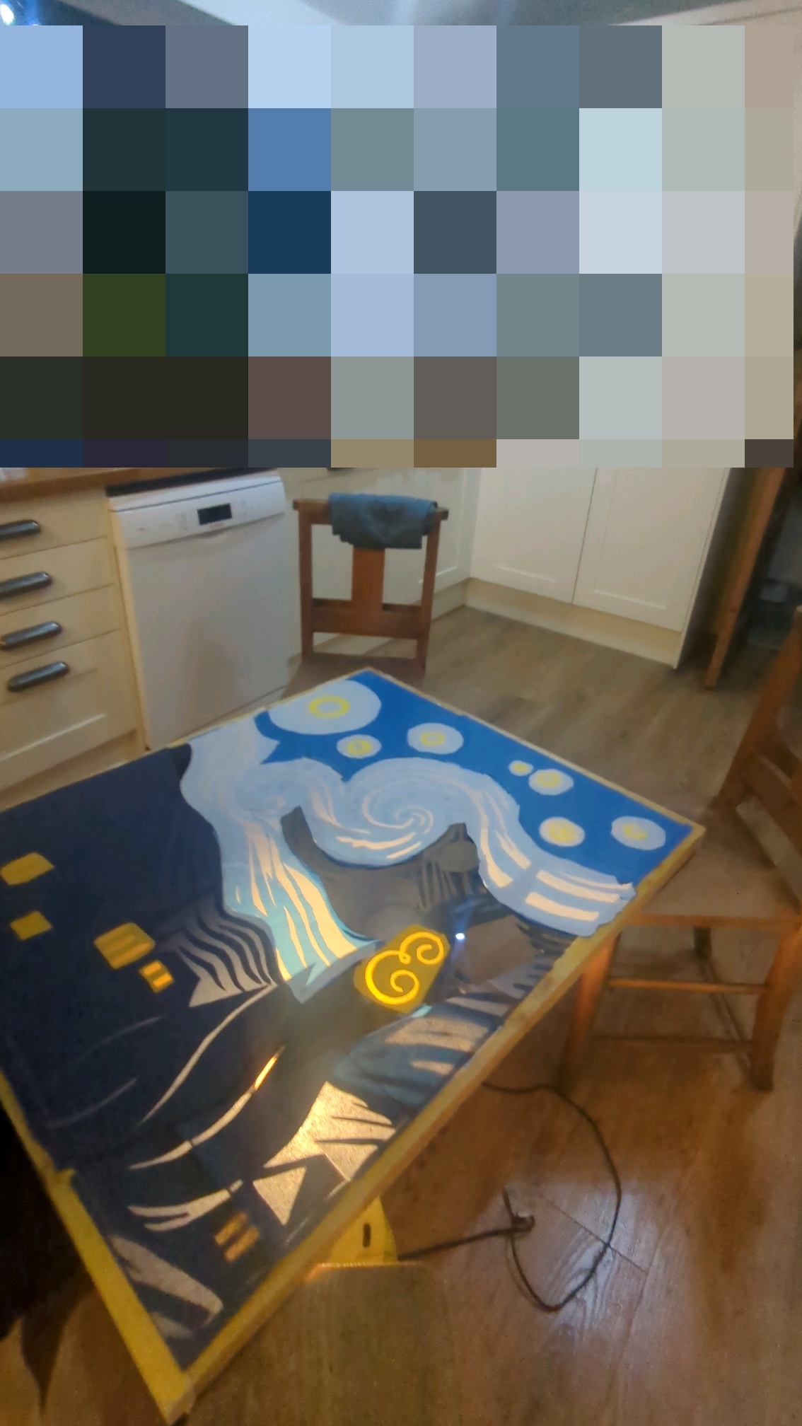 A partially completed advent window suspended on 3 chairs.